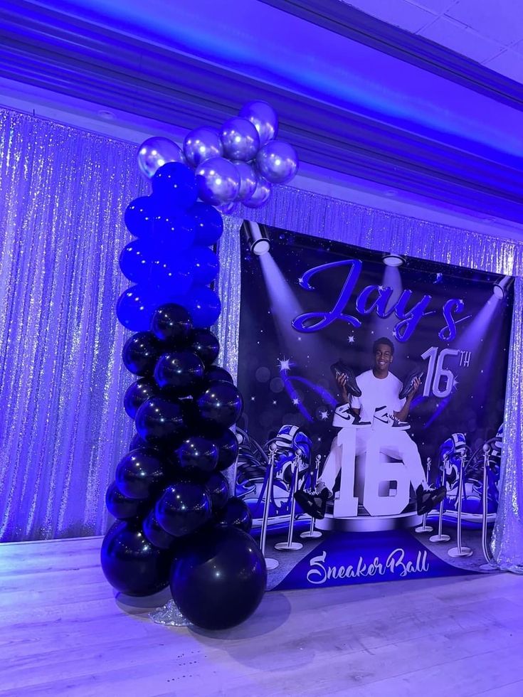 balloons and decorations are set up in front of a stage backdrop for a birthday party