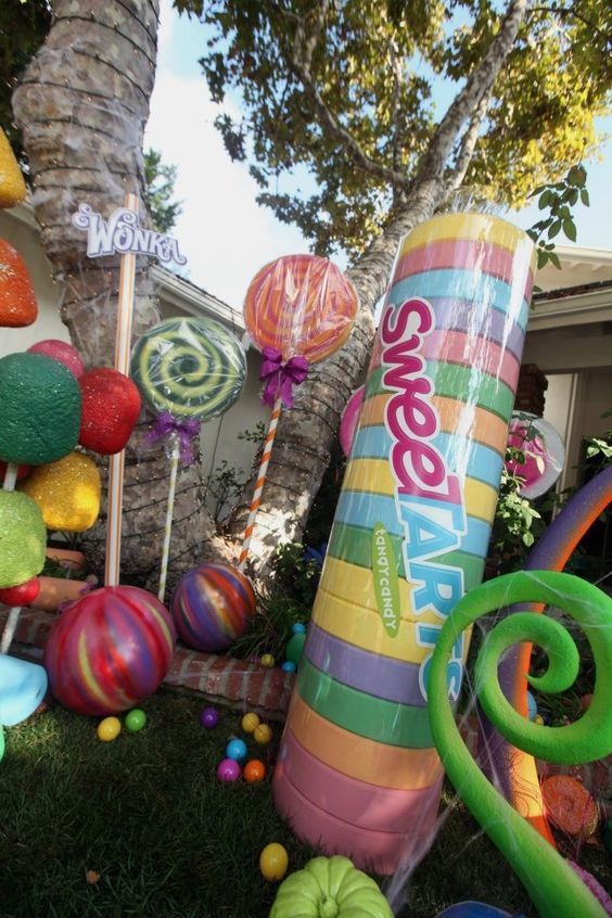 an assortment of colorful balloons and decorations in front of a house