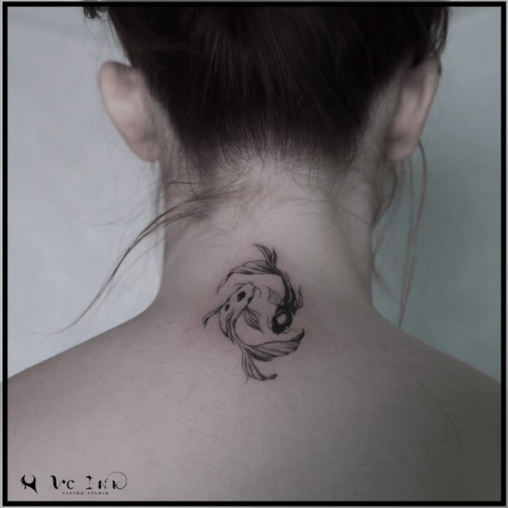 a woman's back neck with a fish tattoo on her left side ribcage