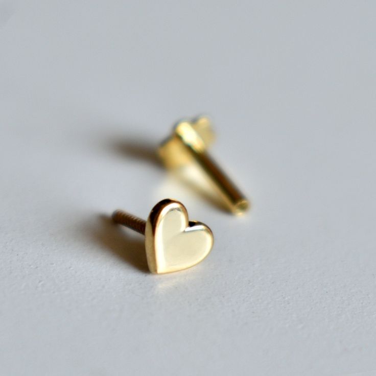 "Sweet little solid gold Heart stud, handcrafted in 14k gold, this pin is available in a variety of closure options for different types of piercings. A cute stud for all ages! * Gold - 14K Solid Gold * 4mm*4mm * Standard length of the post below design is 6-7mm. It can be adjusted as per requirements as well. DIAMOND NOSE PIN : https://www.etsy.com/listing/267480507/ ROUGH EMERALD NOSE STUD : https://www.etsy.com/listing/267480037/ If you like this pin, please press \"Pin it\" button on the righ Dainty 14k Gold Cartilage Earrings For Gift, 14k Yellow Gold Cartilage Earrings For Gift, Dainty 14k Gold Cartilage Earrings As Gift, 14k Yellow Gold Cartilage Earrings, Dainty Tiny Gold Heart Earrings, Gold Heart Cartilage Earrings For Everyday, Gold Heart-shaped Cartilage Earrings, Everyday Gold Heart Cartilage Earrings, Hypoallergenic Yellow Gold Cartilage Earrings As Gift