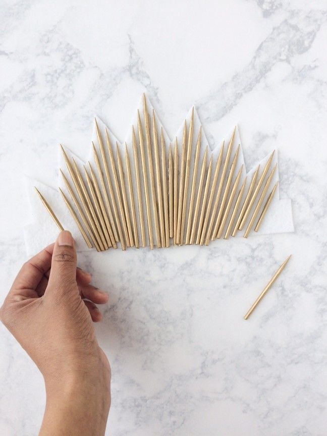 a person is holding up some wooden sticks on a marble surface with one hand and the other