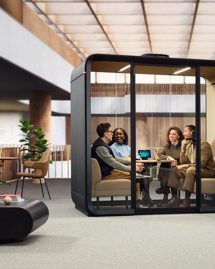 a group of people sitting at a table in a room with glass walls and doors