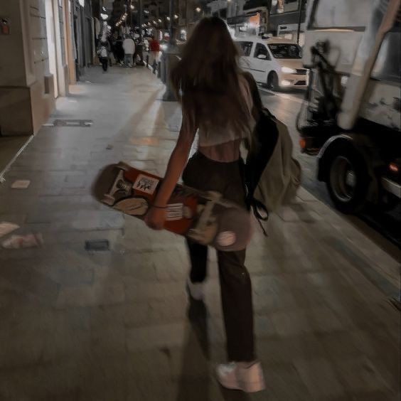 a woman is walking down the street with her skateboard