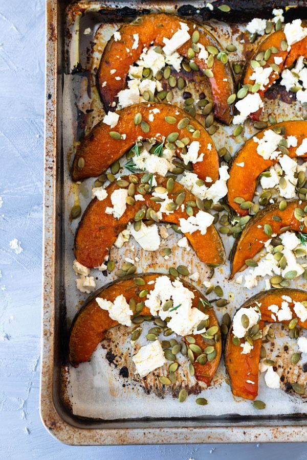 roasted pumpkins with feta cheese, rosemary and pepita in a baking pan