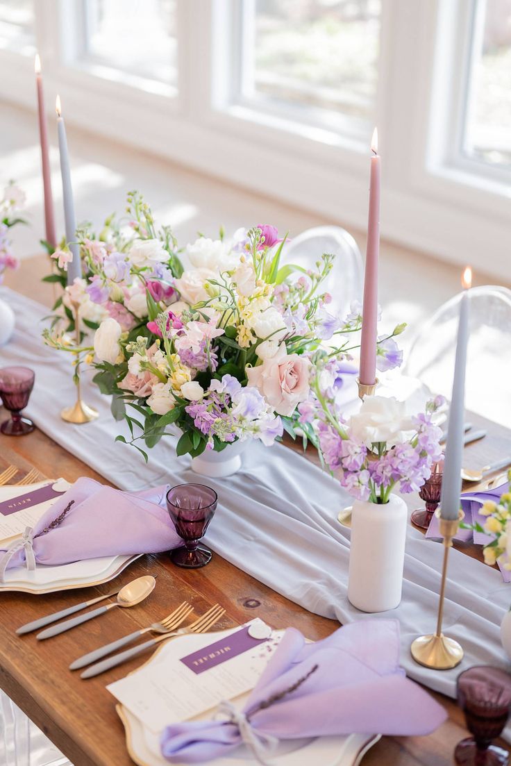 the table is set with purple and white flowers