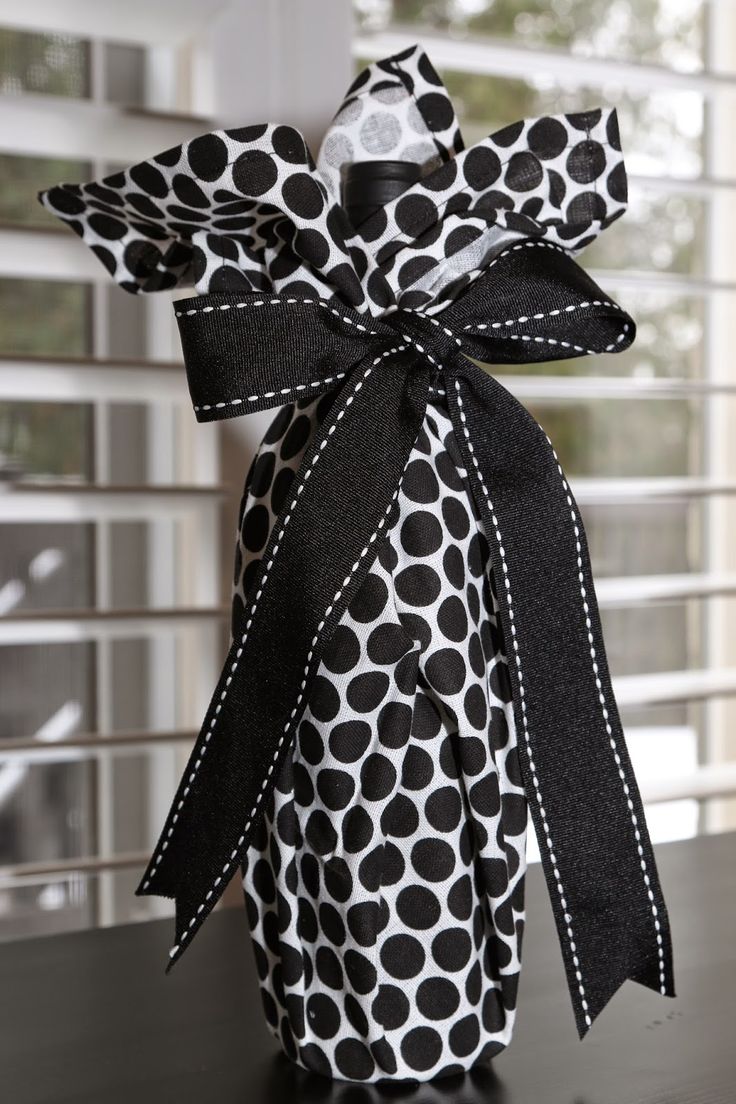 a bottle wrapped in black and white polka dot paper with a bow on the top