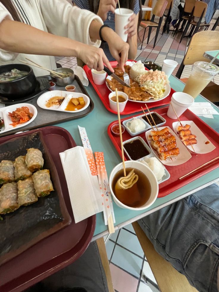 people sitting at a table with plates of food and drinks in front of them on trays