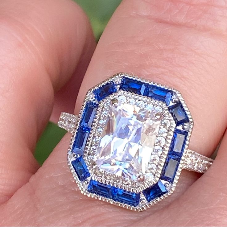 a woman's hand holding an engagement ring with blue and white stones