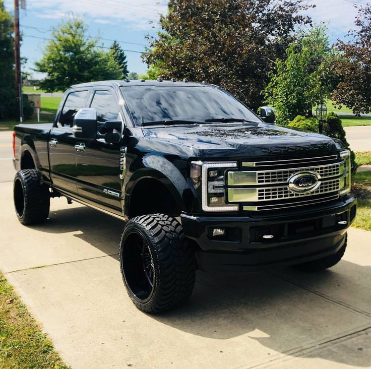 a large black truck parked on top of a sidewalk