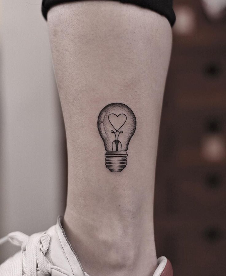 a small lightbulb tattoo on the back of a woman's right leg