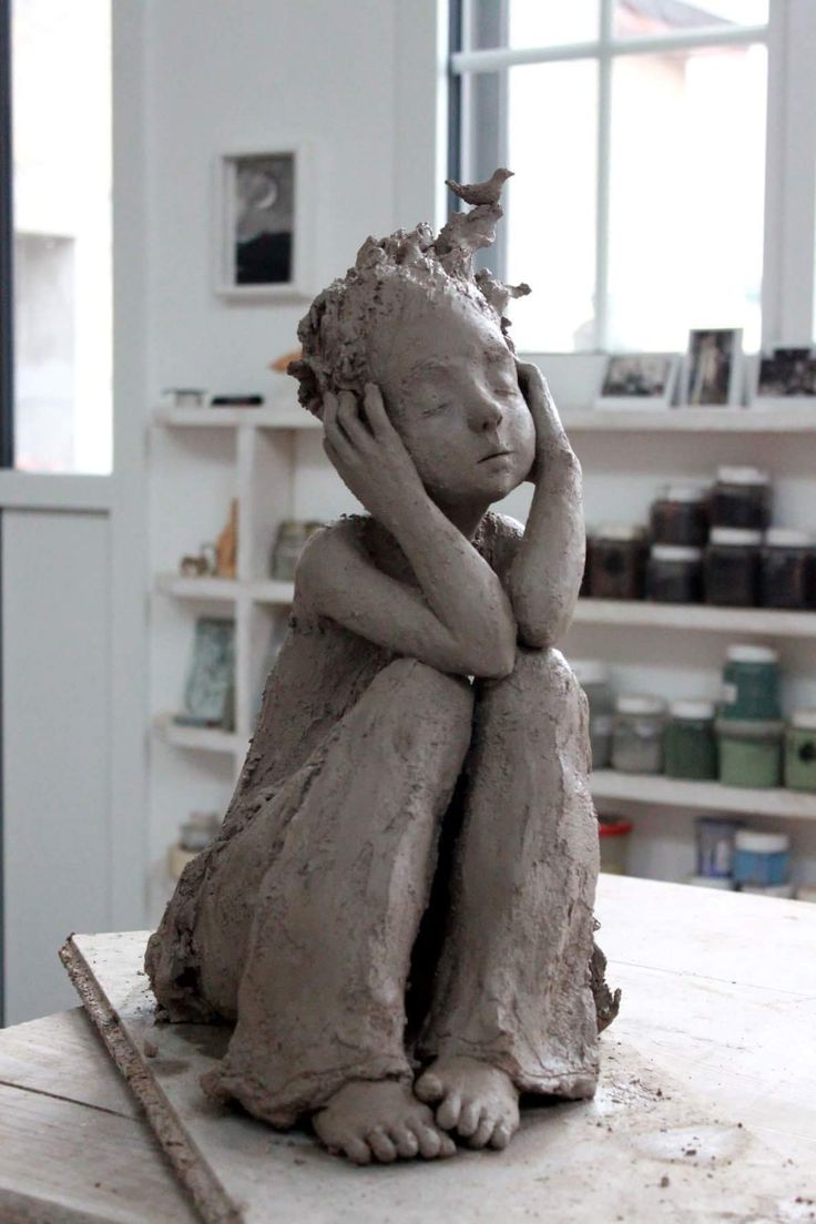 a clay sculpture of a child sitting on top of a table