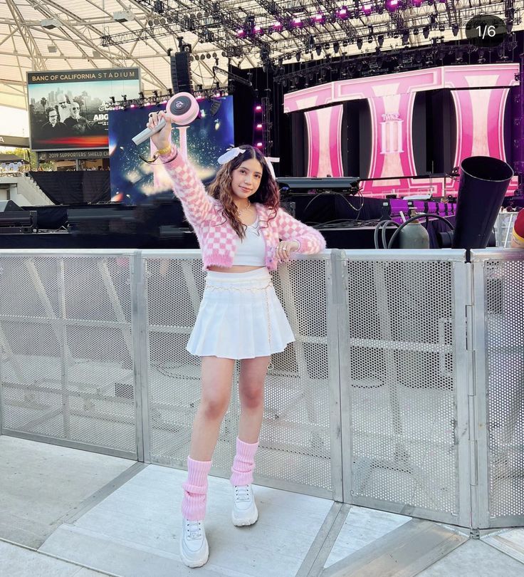 a girl in a pink and white outfit is holding her hands up to the air