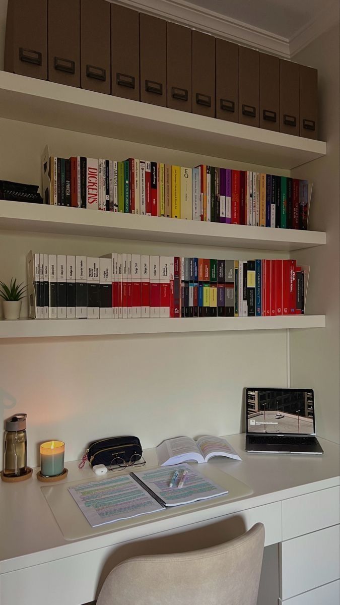 a desk with a laptop computer and books on the shelves above it, along with other office supplies