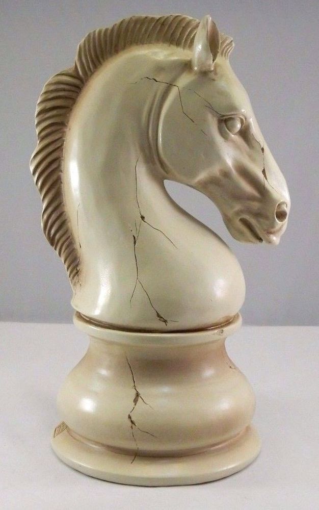 a white horse head statue sitting on top of a wooden base with the words home and garden essentials below it