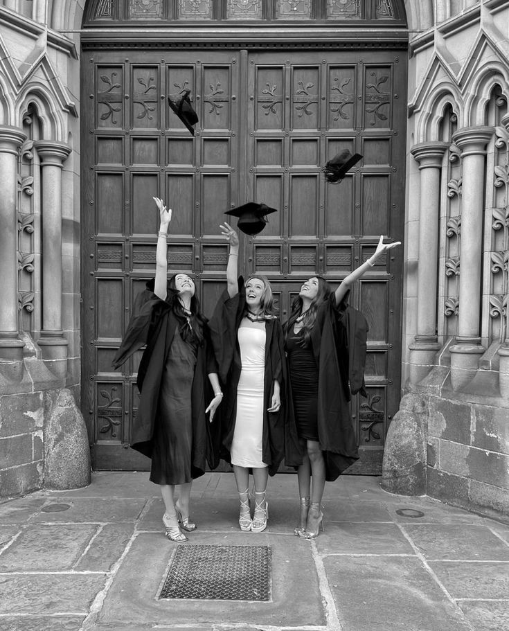 three women in graduation gowns are throwing their hats into the air while posing for a black and white photo