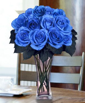 a vase filled with blue roses on top of a wooden table