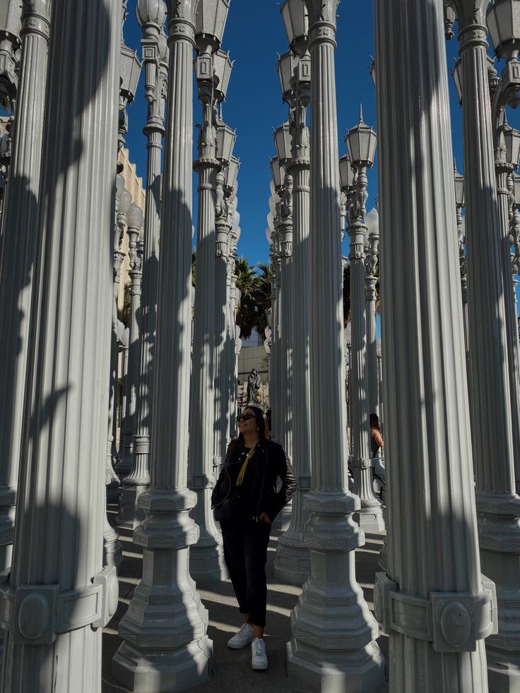 a woman is standing between many white pillars