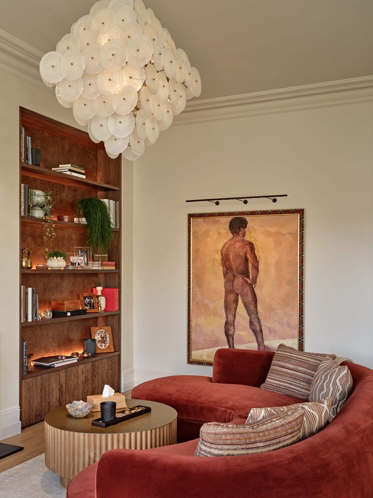 a living room with two red couches and a large painting hanging on the wall