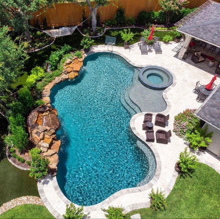 an aerial view of a swimming pool with lounge chairs and trees in the back yard