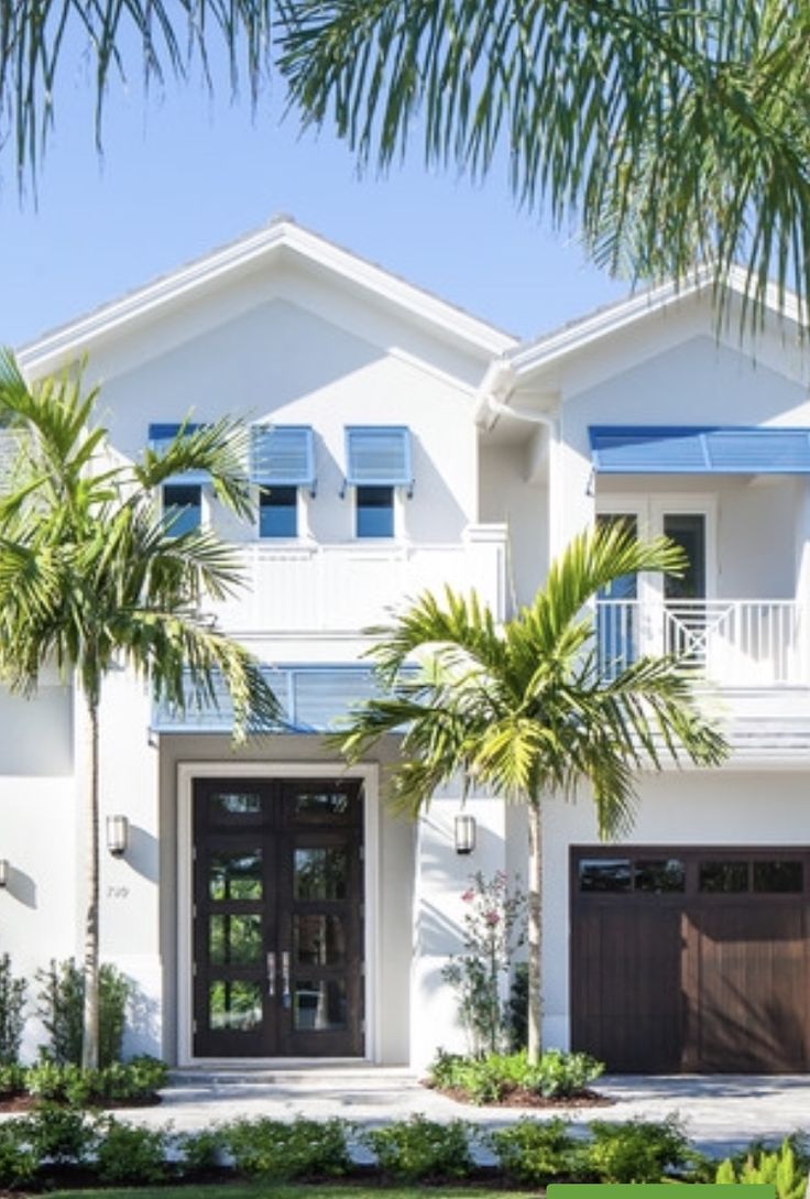 a white house with blue shutters and palm trees