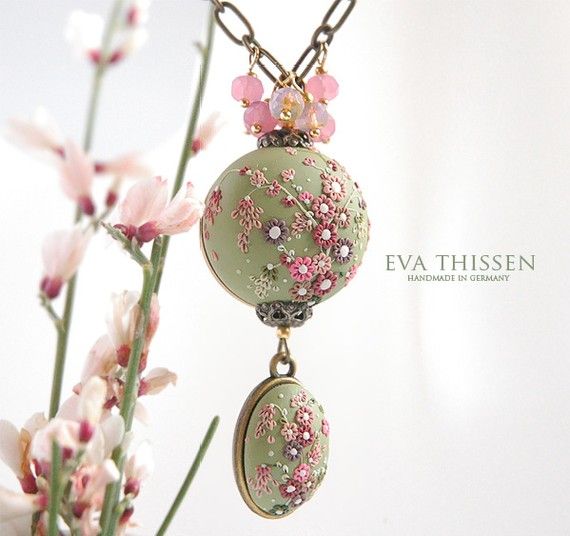 a close up of a vase with flowers in it and a necklace hanging from the front