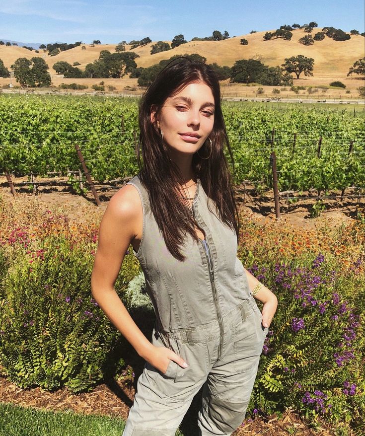 a woman standing in the grass with her hands on her hips