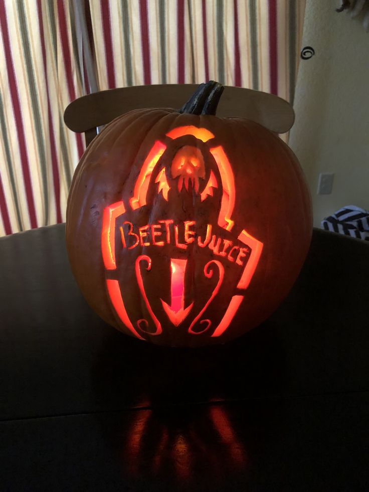 a pumpkin carved to look like the beetlejuice logo is sitting on a table