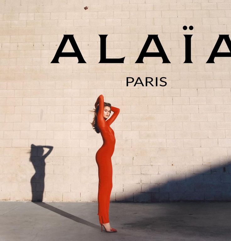 a woman standing in front of a wall with the word alla paris on it's side