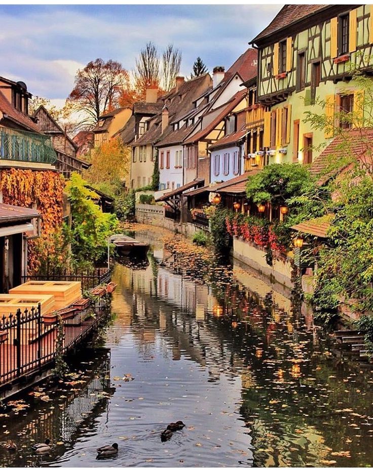 a river running through a small town next to tall buildings with windows on each side