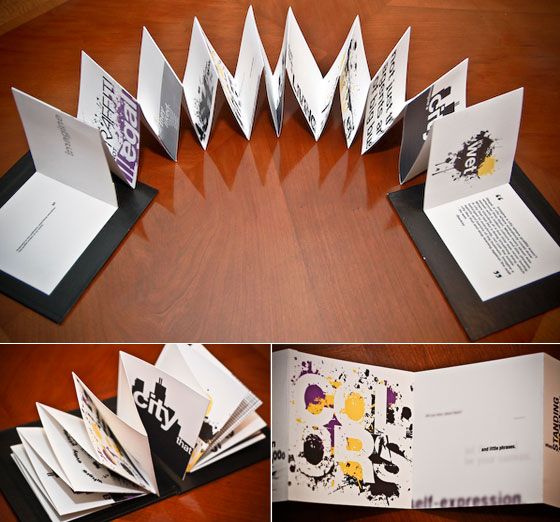 an open book on top of a wooden table next to some folded up books and papers