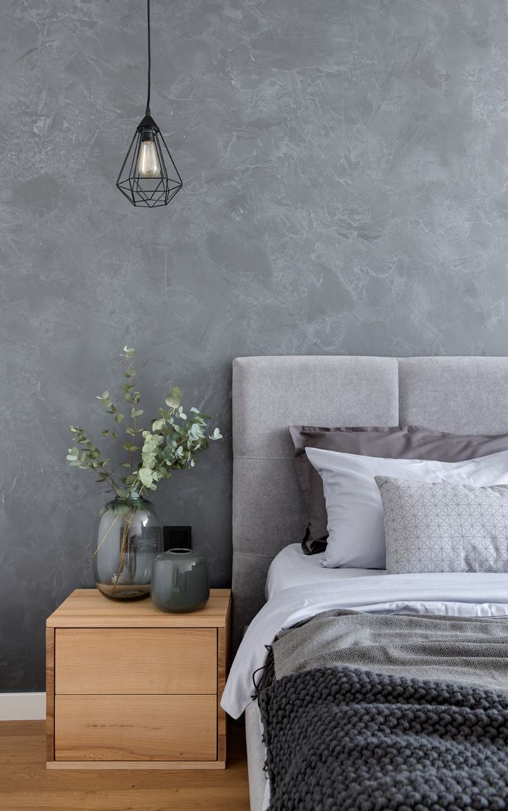 a bedroom with grey walls and white bedding, two vases on the nightstand