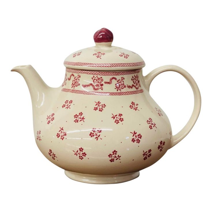 a white tea pot with red flowers on it