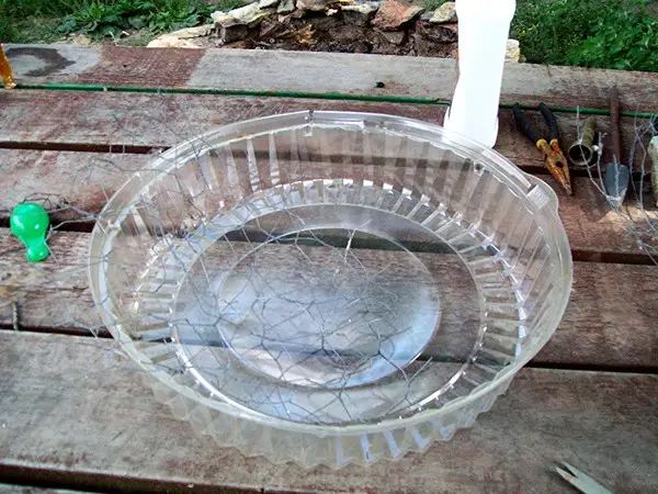 a clear glass bowl sitting on top of a wooden table next to a green bottle