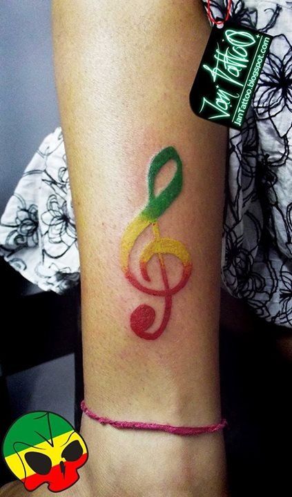 a person with a colorful tattoo on their arm that has music notes painted on it