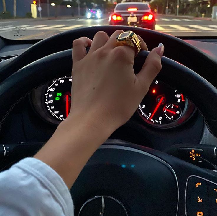 a person driving a car with their hand on the steering wheel and dashboard lights behind them