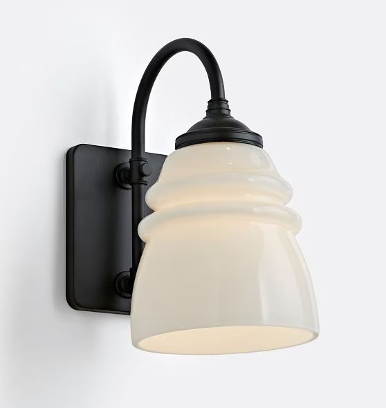 a black and white light mounted on a wall next to a lamp fixture with a glass shade