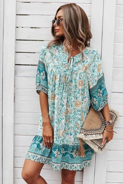 A woman in sunglasses stands against a white wooden wall, wearing the trendy Ruston Floral Boho Dress from Western Edge Boutique in floral turquoise and beige. She holds a woven clutch with tassels, her wavy hair flowing as she looks off to the side on this perfect summer day. Teal Floral Dress, Floral Boho Dress, Beautiful Floral Dresses, Keep It Cool, Romantic Evening, Boho Floral Dress, Summer Day, Dress Romper, A Romantic