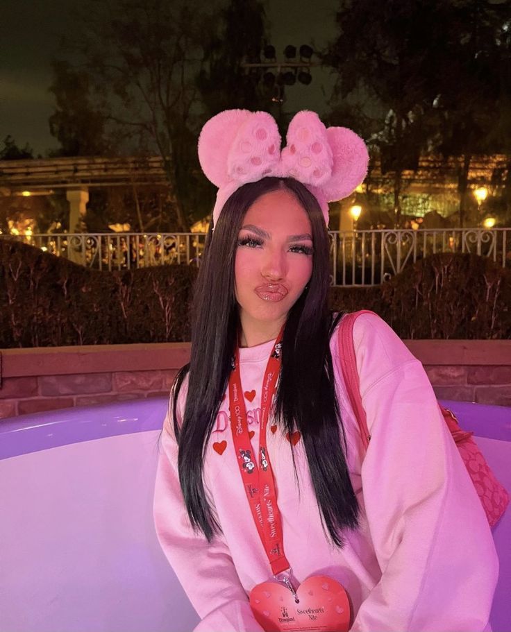 a woman with long black hair wearing pink bunny ears and holding an apple in her hand