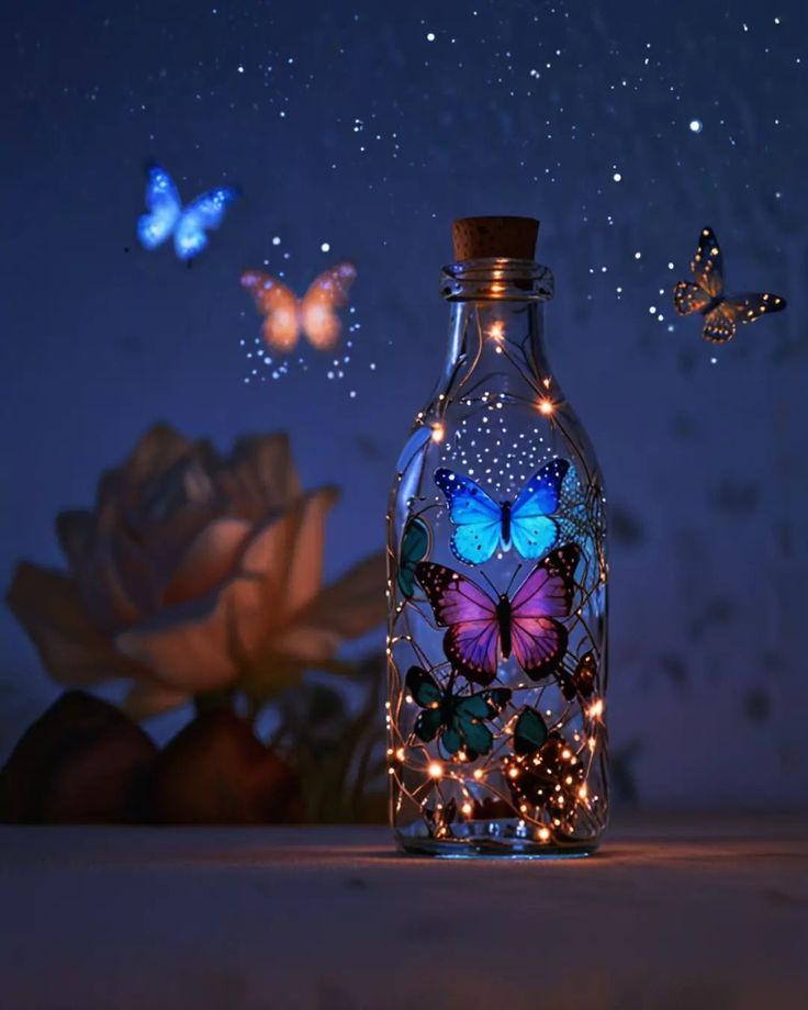 a bottle that has some lights in it with butterflies flying around the bottle and on the table