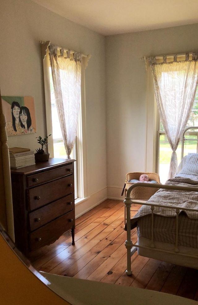 a bed room with a neatly made bed and wooden floors