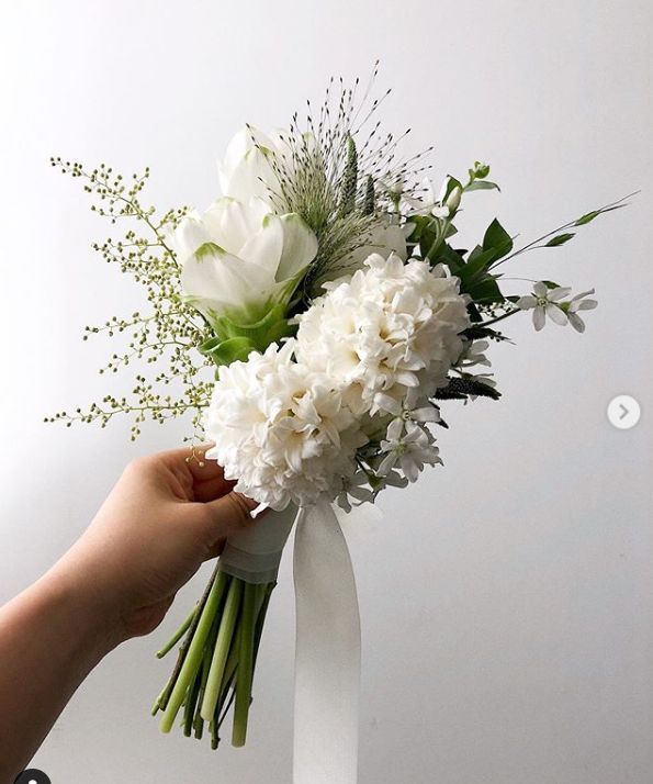 a bouquet of flowers being held by a person's hand on a white background