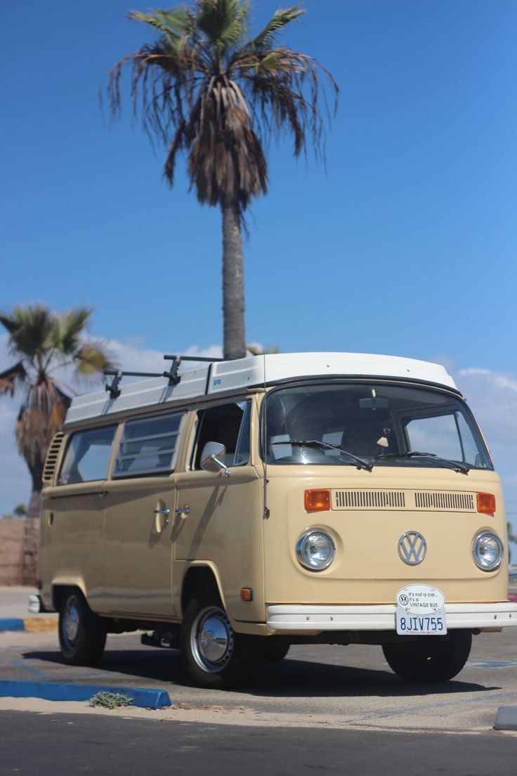 an old vw bus parked on the side of the road with a palm tree in the background