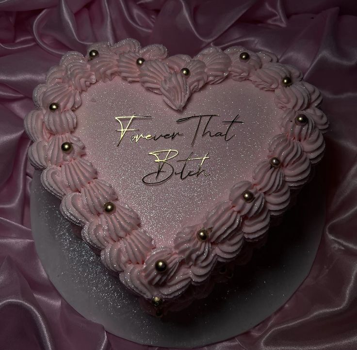 a pink heart shaped cake with writing on it