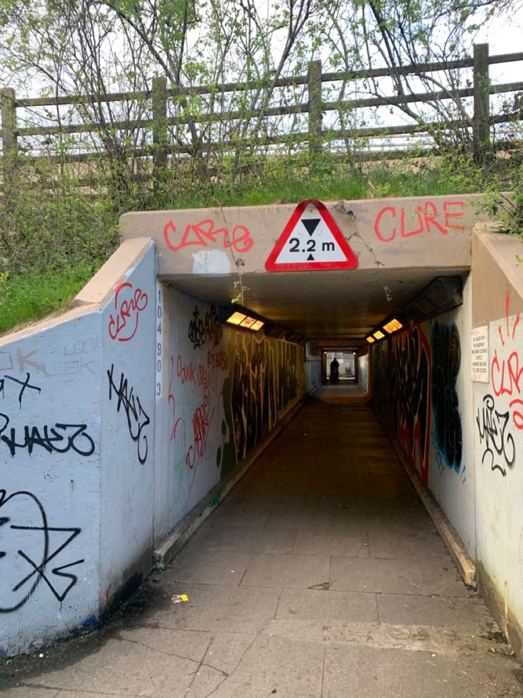 a tunnel with graffiti on the walls and below it is a sign that says curvy