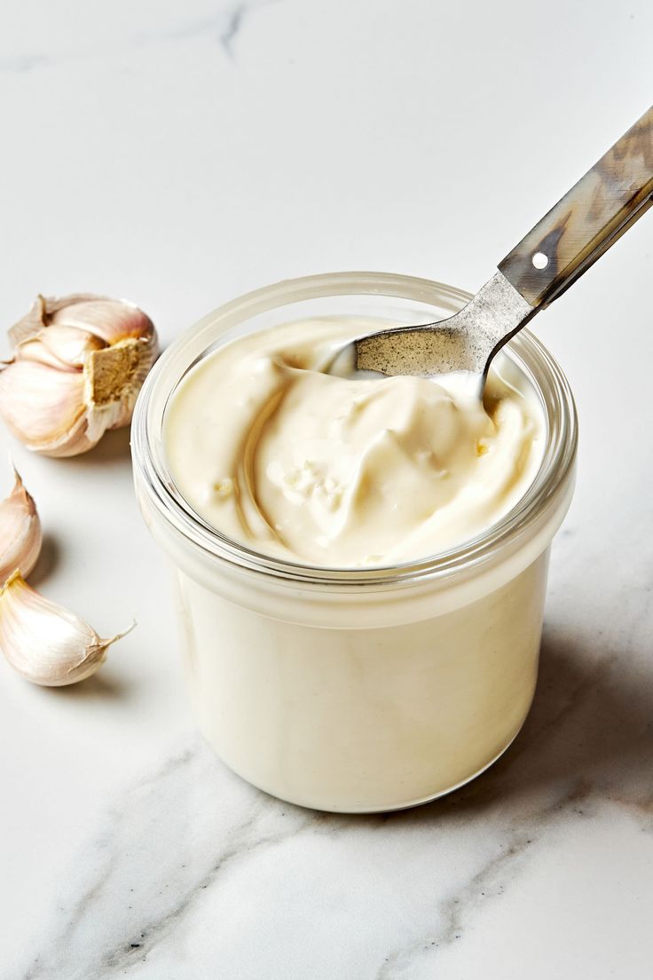 a jar filled with cream next to garlic