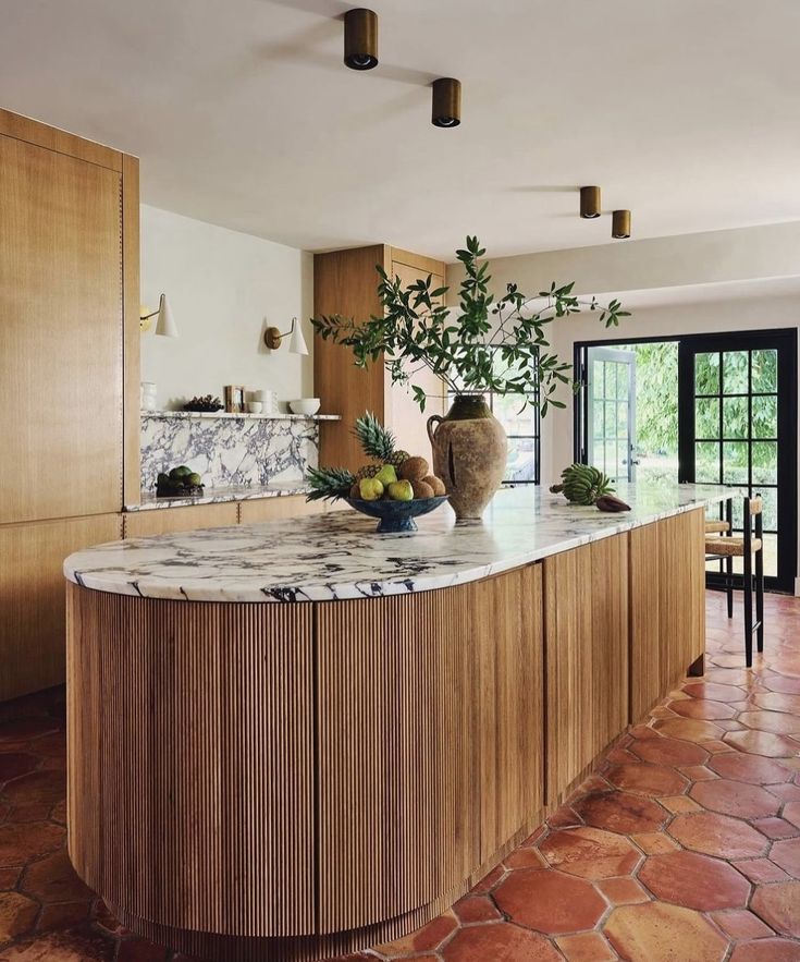 a large kitchen with marble counter tops and wooden cabinetry, along with potted plants