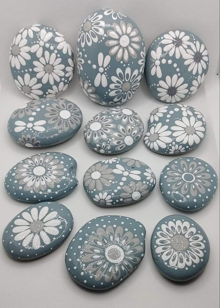 several blue and white painted rocks with flowers on them