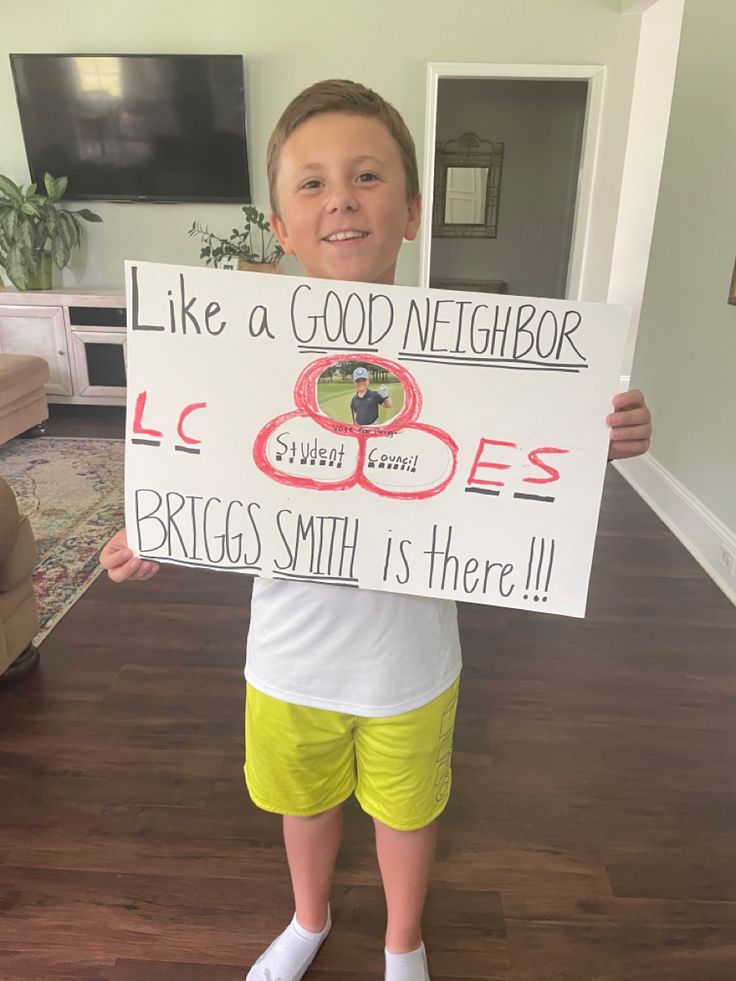 a young boy holding up a sign that says like a good neighbor