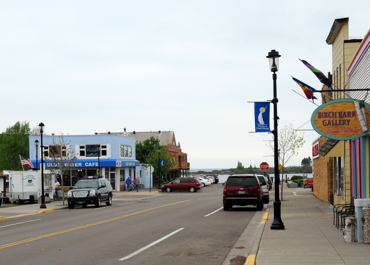 cars are driving down the street in front of shops and businesses on a cloudy day