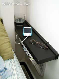 an ipod is plugged into the side of a bed with glasses sitting on it